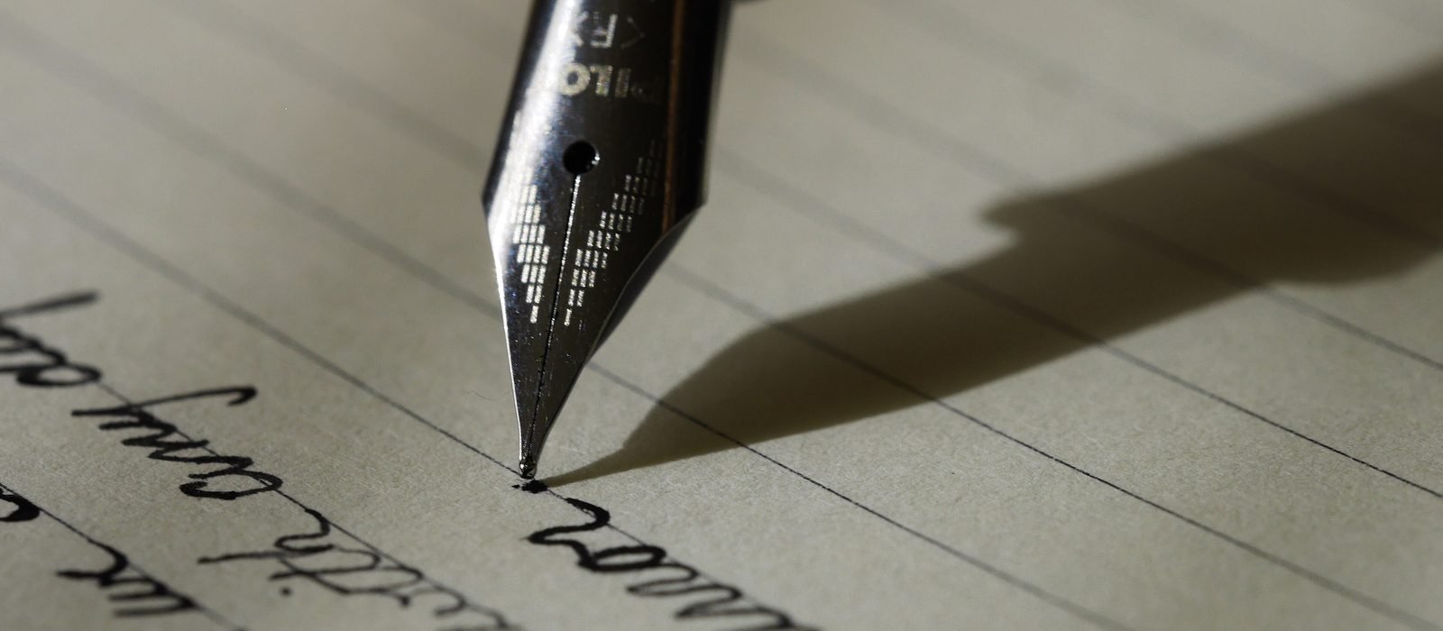 Close-up of a fountain pen nib writing in longhand on lined paper